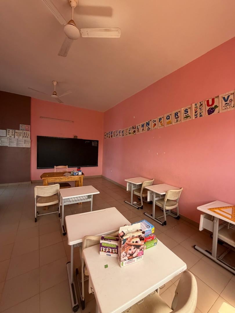 Salle rose avec affiches d'alphabet, bureau de l'enseignant et télévision — section Petite et Moyenne Section
