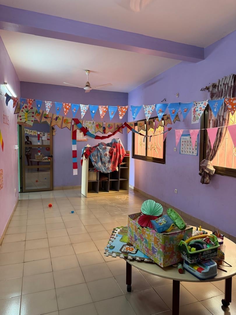 Salle de jeux violette avec fanions et bacs de rangement — Complexe Rokia Traoré